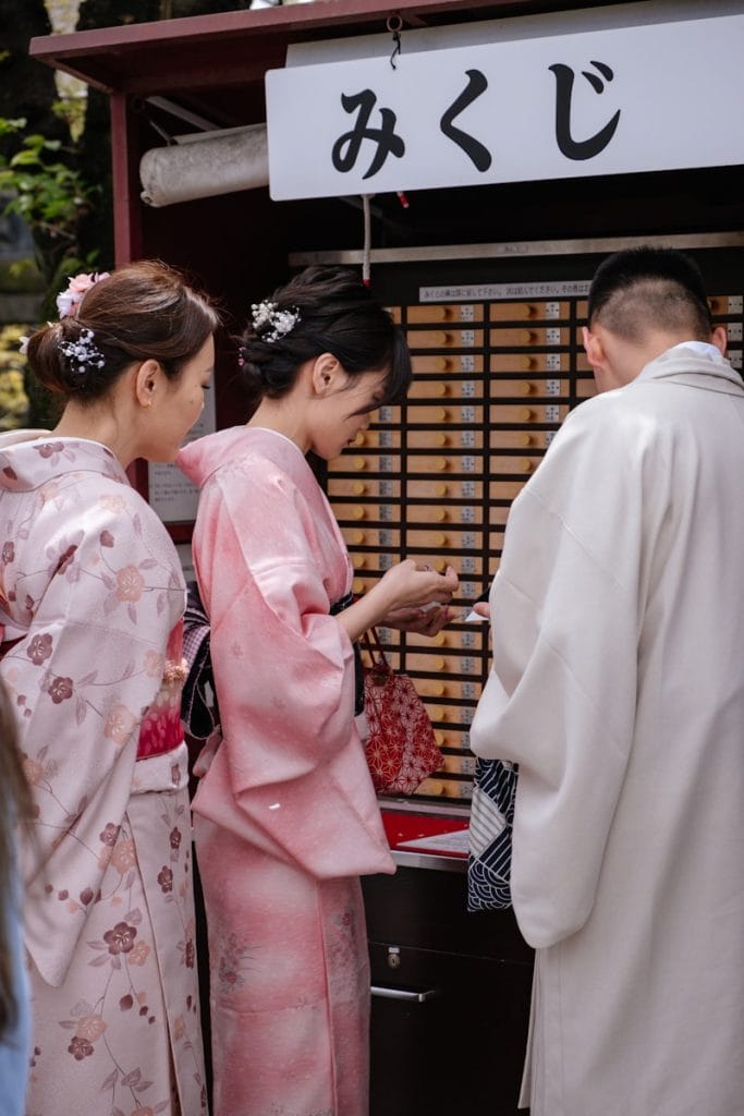 People in kimonos draw fortunes from a japanese shrine.